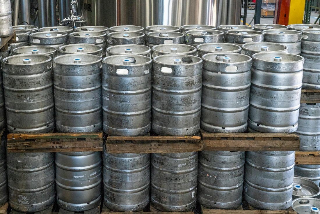 Stacked stainless kegs at a brewery — illustrating half barrel and sixtel keg sizes