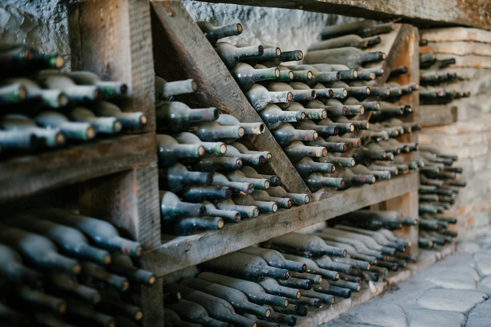 Rows of wine bottles with their front labels facing out on a shelf
