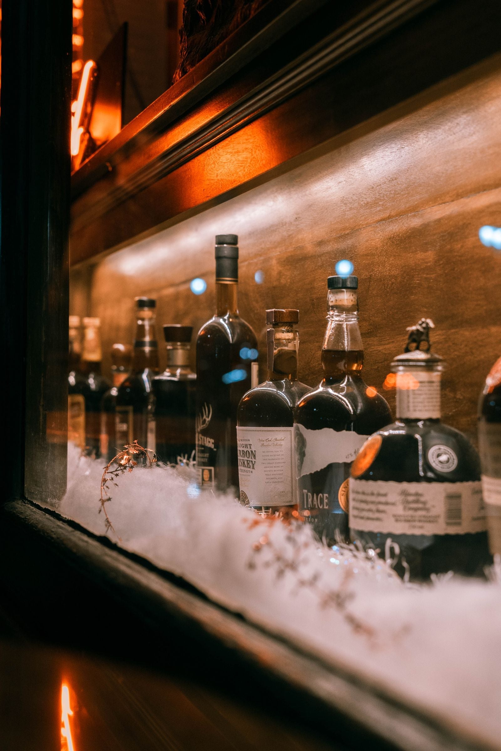 Bottles of bourbon, Scotch, rye, and Irish whiskey on a bar shelf